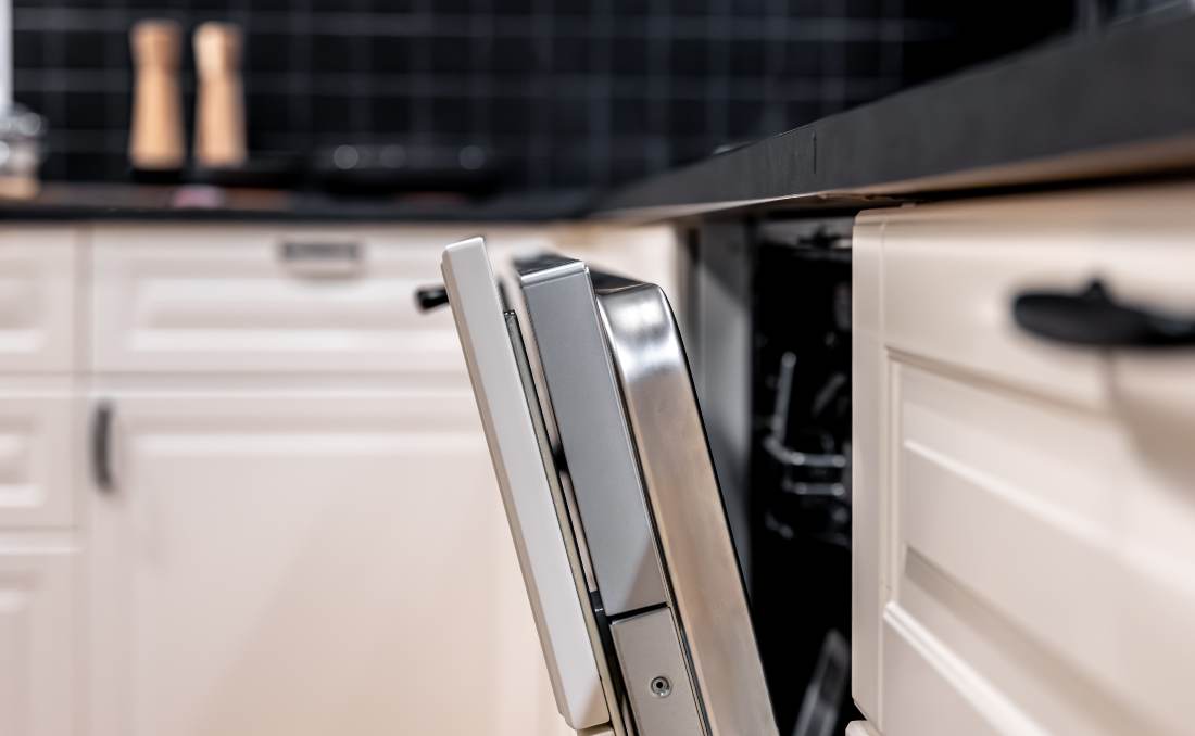 Ugradna mašina za sudove sa blago otvorenim vratima u savremenoj kuhinji.