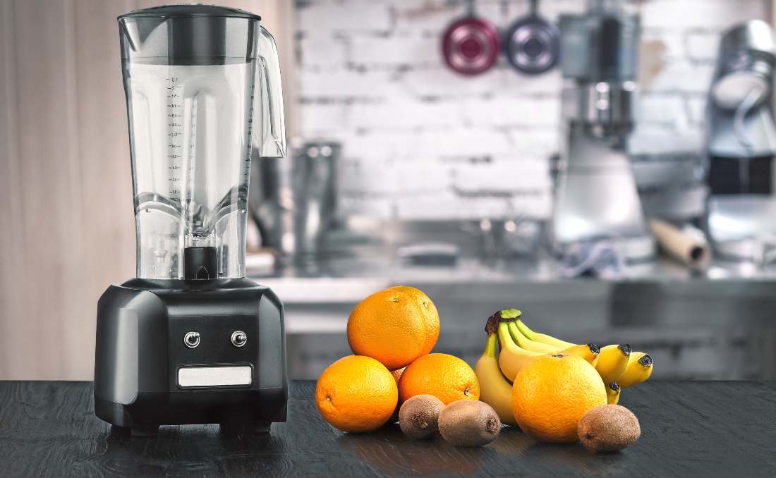 Sokovnik za hladno ceđenje na kuhinjskom pultu sa svežim voćem