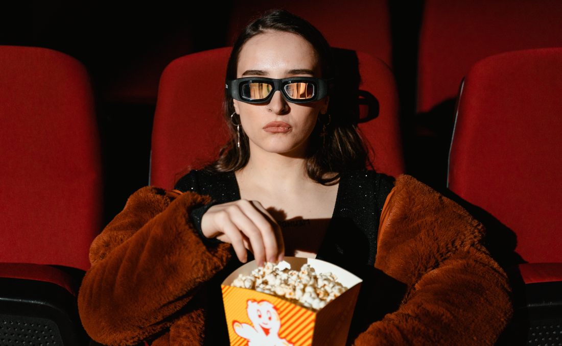 Devojka sa 3d naočarima u bioskopu gleda film i jede kokice