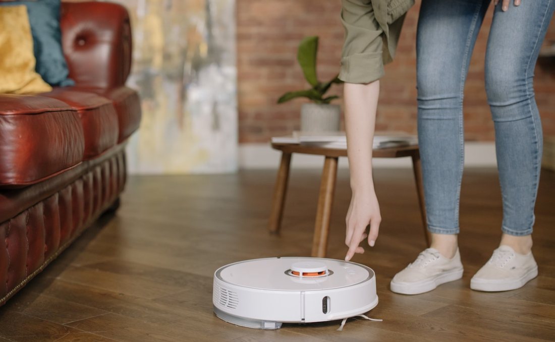 Čovek uključuje robot usisivač