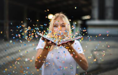 Devojka koja duva konfete iz otvorene knjige.