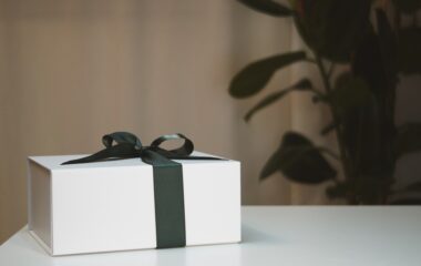 Poklon za slavu u beloj kutiji sa crnom mašnom na stolu.