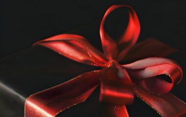 Crni poklon sa elegantnom crvenom mašnom.