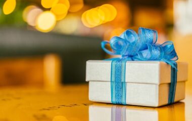Poklon u beloj kutiji sa plavom mašnom.