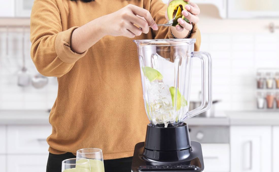 Blender u kojem žena stavlja avokado.
