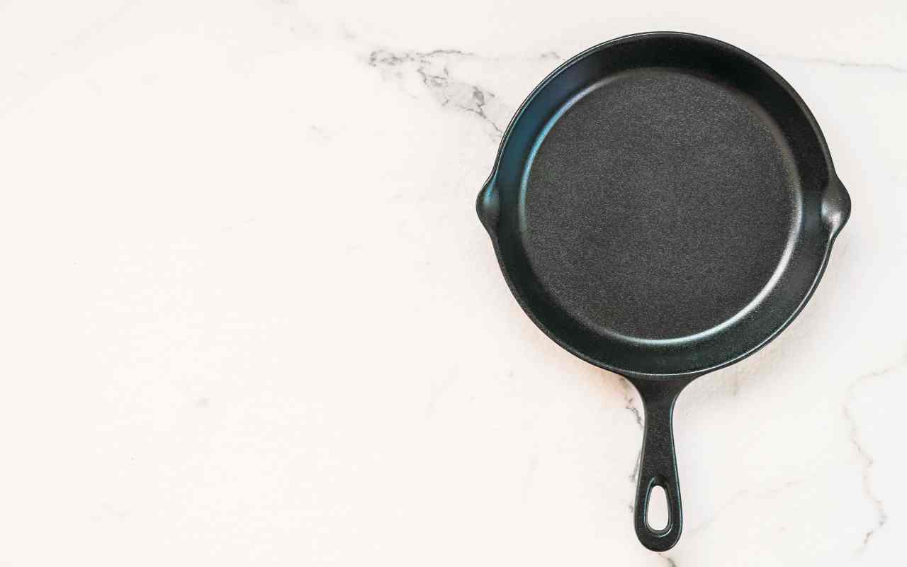 Tiganj od livenog gvožđa na svetloj podlozi.