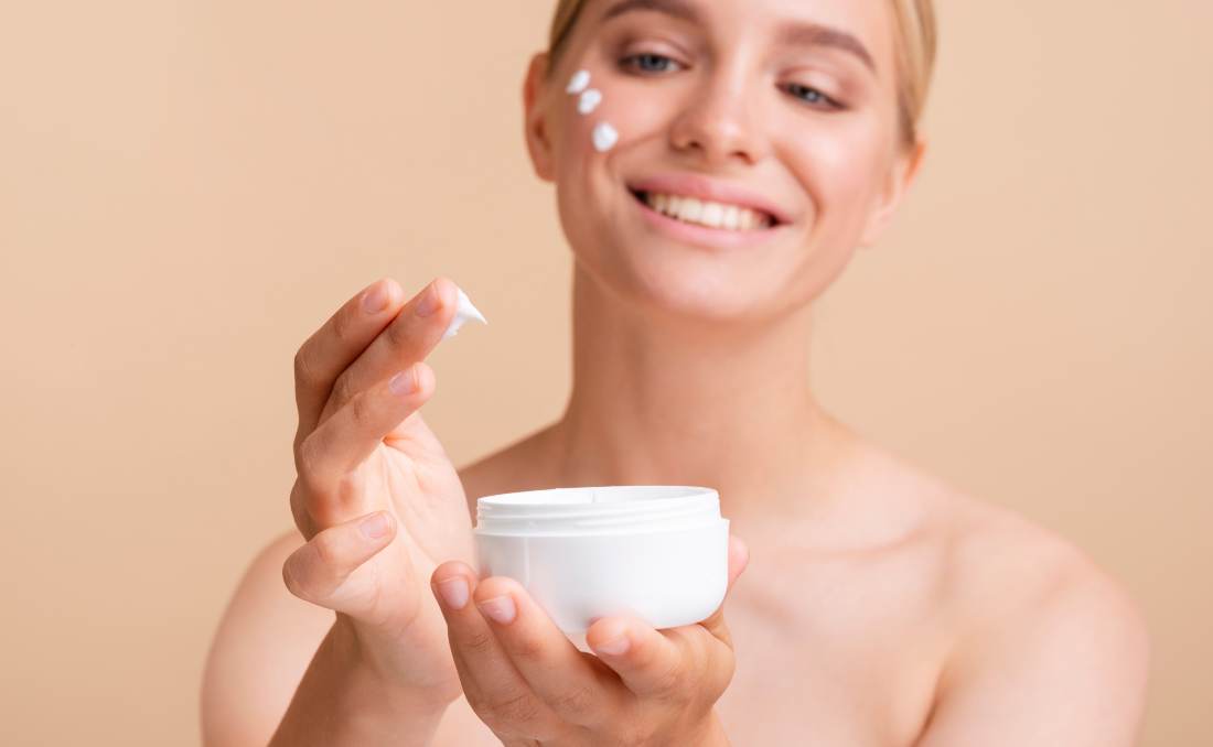 Devojka nanosi kremu na lice tokom svakodnevne nege kože.