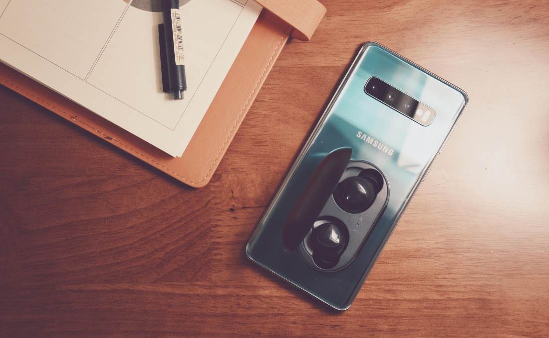 Pametni samsung telefon na stolu uz slušalice.