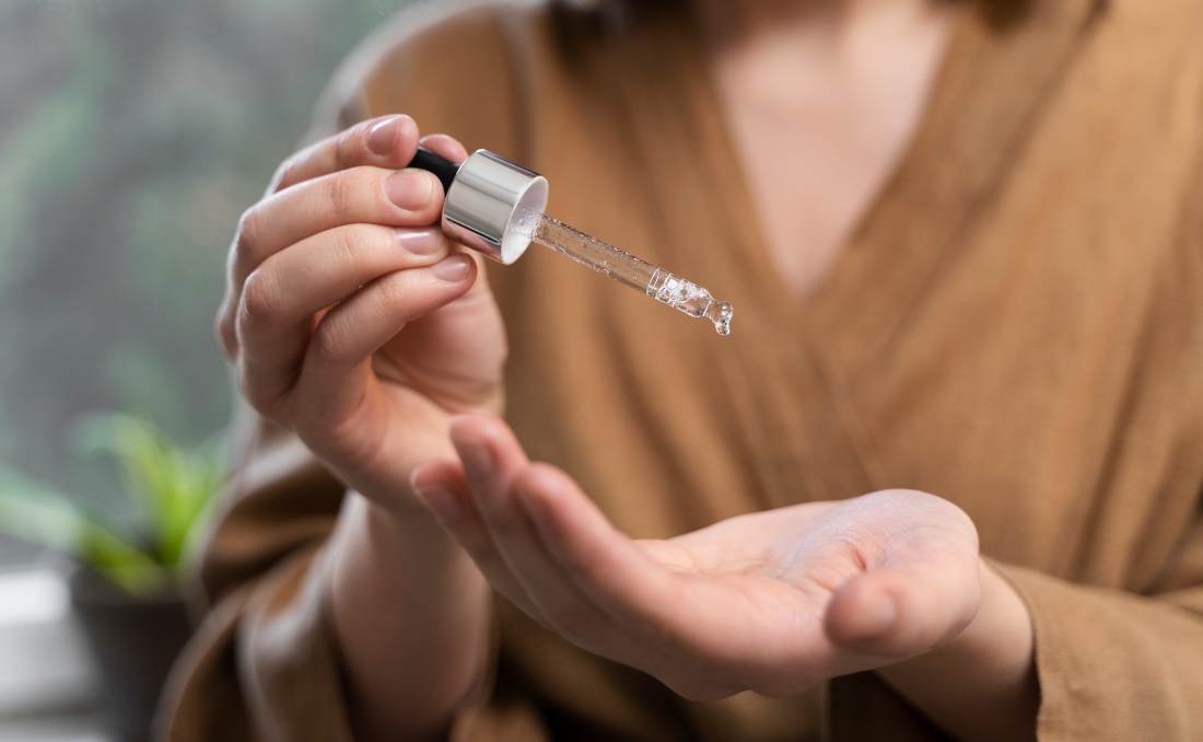 Mlada žena nanosi serum na lice.