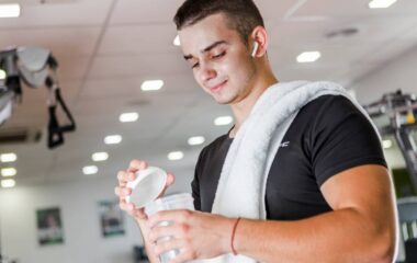 Muškarac u teretani drži šejker u ruci.